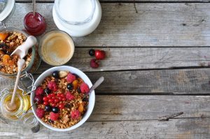 Healthy breakfast with granola, berries, milk, honey and coffee