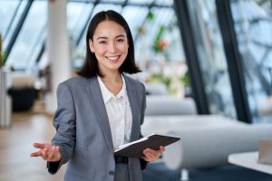 Happy young Asian saleswoman looking at camera welcoming client