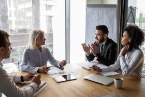 Group of business employees discussing topics at a table.
