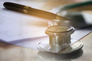 Stethoscope on a table with a pen and paper.