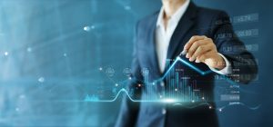 A man in a business suit is standing in front of a virtual board and drawing a graph.