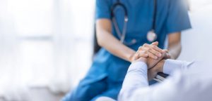 A health professional is holding the hands of a patient.