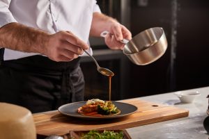 saucier chef putting sauce on dish
