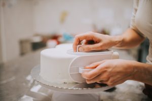 person decorating cake with fondant