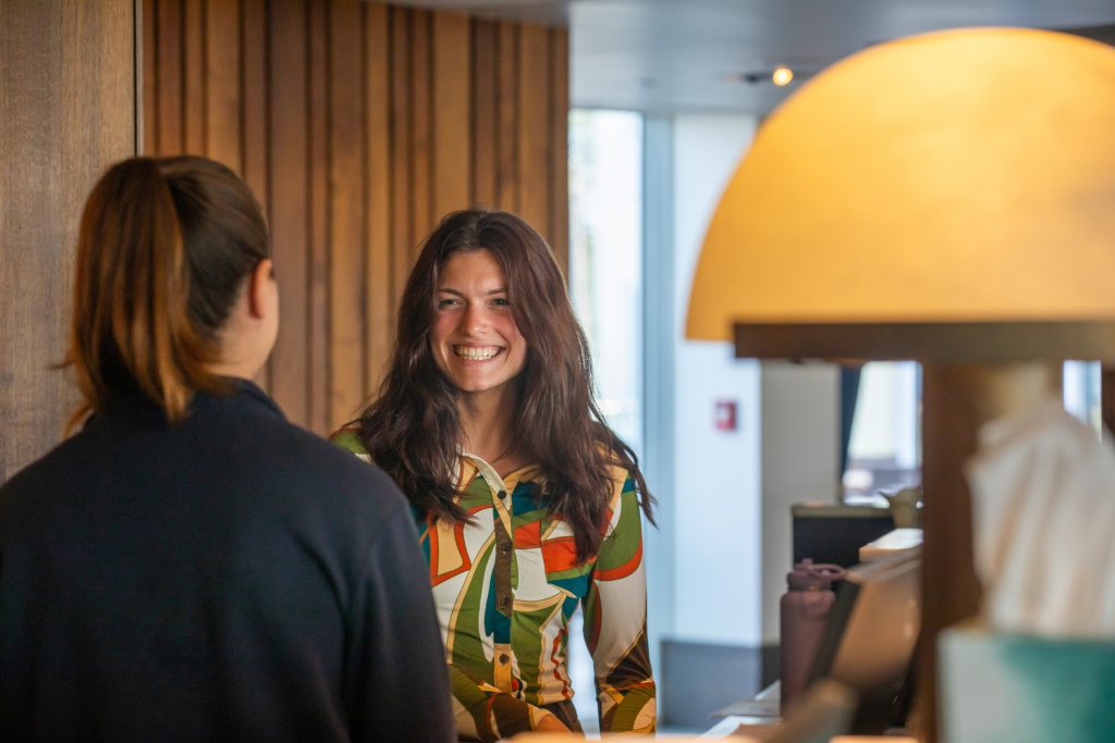 Two young women talking together in the lobby of a hotel.