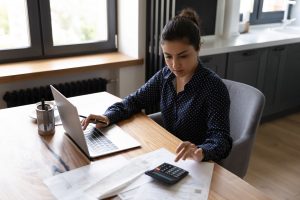 accounting professional using calculator and laptop