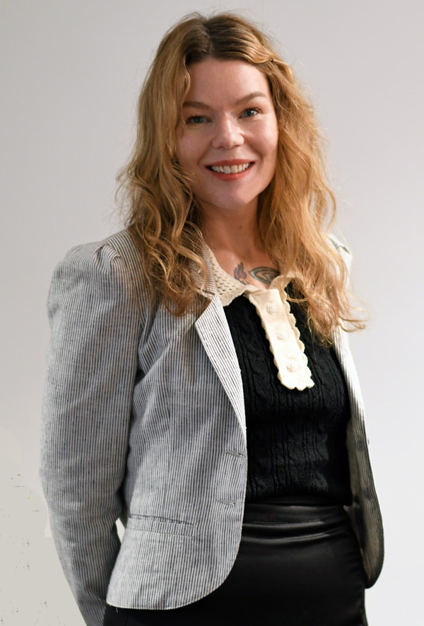 Adriana Milko in a professional grey jacket worn over a black dress.