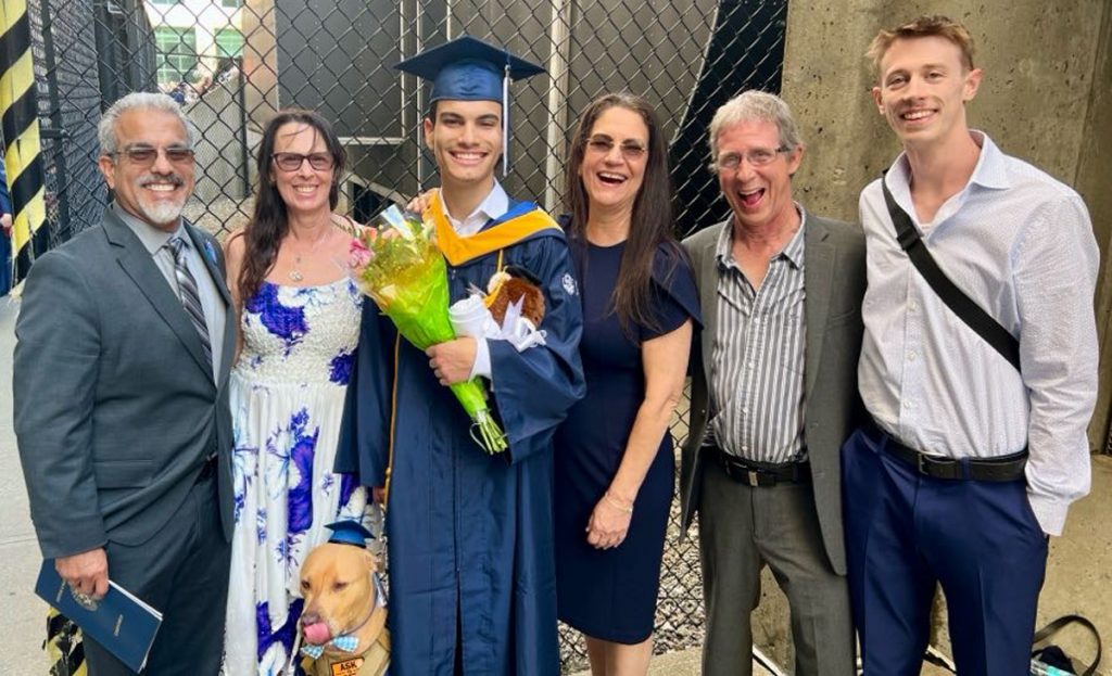 Dasan Orlich in his graduation cap and gown with his partner, family members and dog.