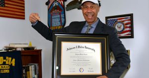 Stephen Senteio poses holding his Doctor of Business Administration degree.