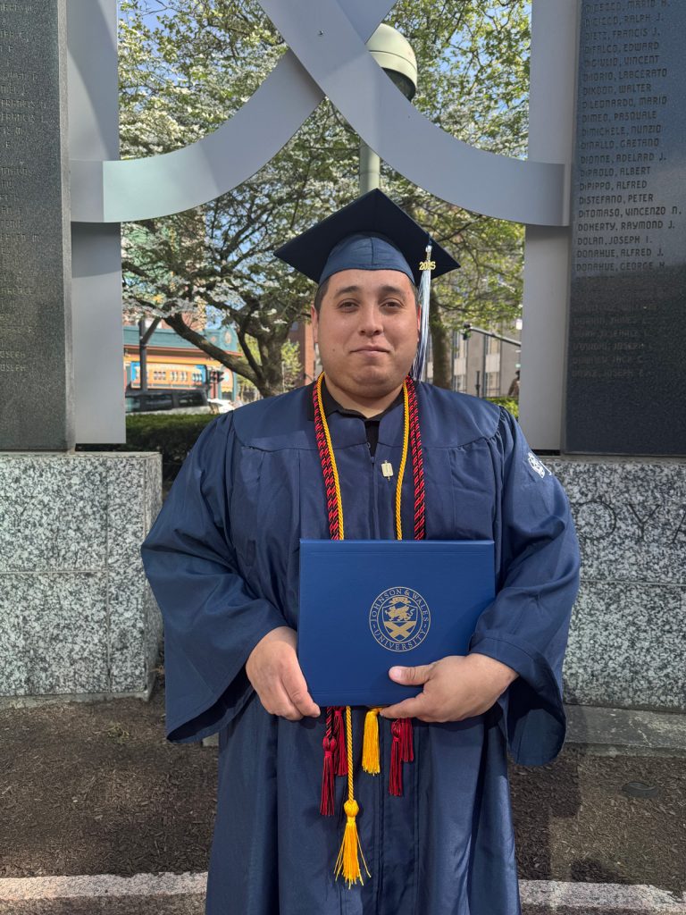 Portrait of Albert Torres in cap and gown, holding the diploma he received at the 2025 Johnson & Wales Commencement ceremony in Providence.