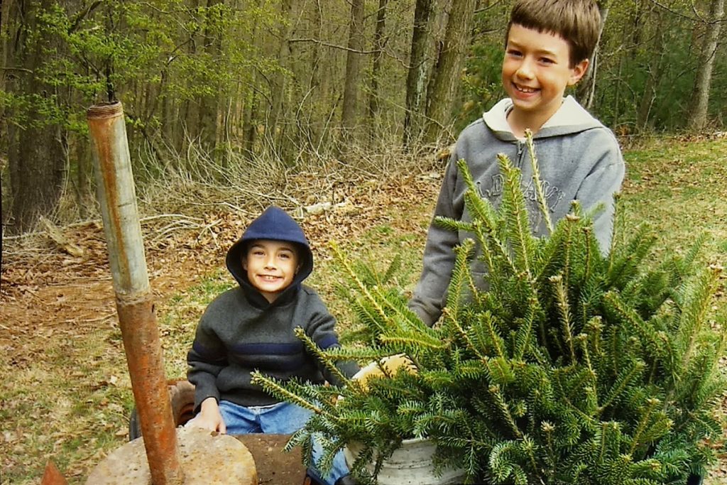 Two young boys - Ben and his brother - plant an evergreen tree on the farm where they were growing up.