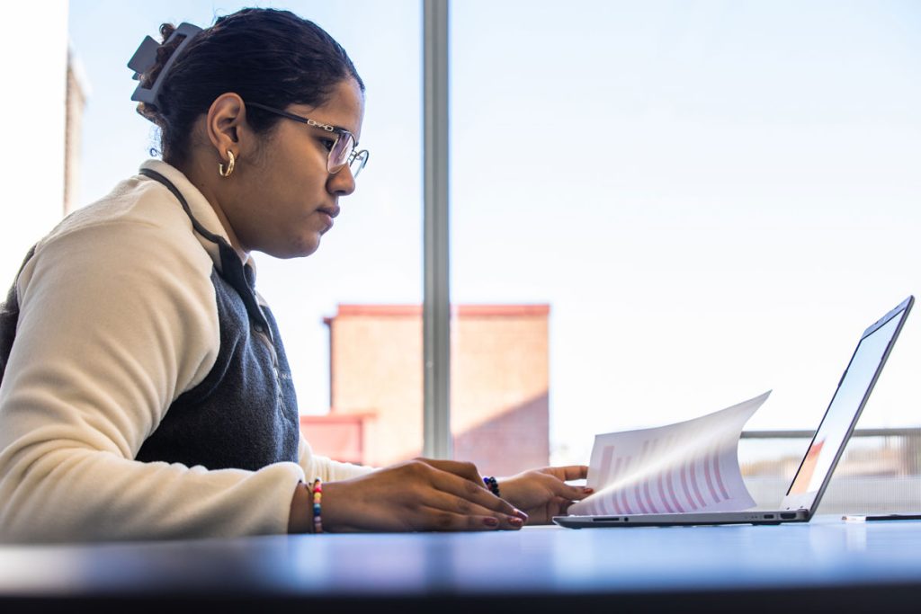 Young woman with laptop performing data analysis.