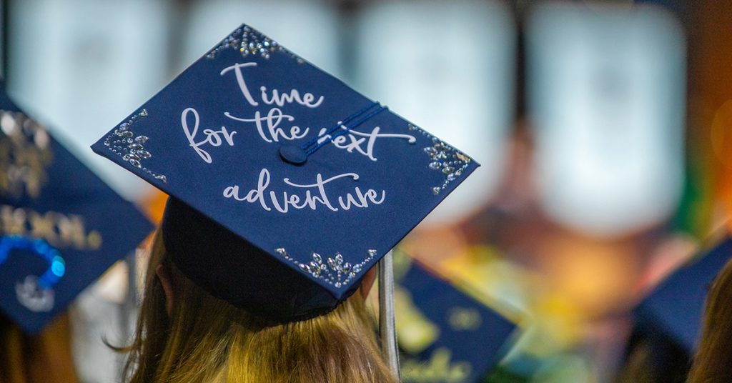 View of the top of a blue graduation cap on which is written in white script, "Time for the next adventure."