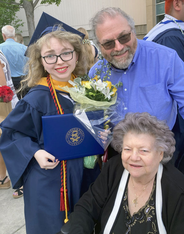 Katherine Campbell in her cap and gown, with her dad and grandmother at the JWU Providence commencement, May 2025.
