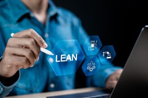 Person using a stylus points to a digital display with the word "LEAN" and icons for technology and automation.