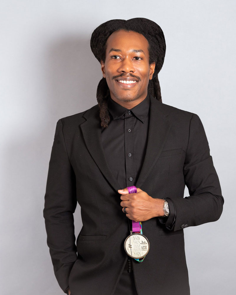 Markeith in a black suit holding a medal he won from a Paralympic event.