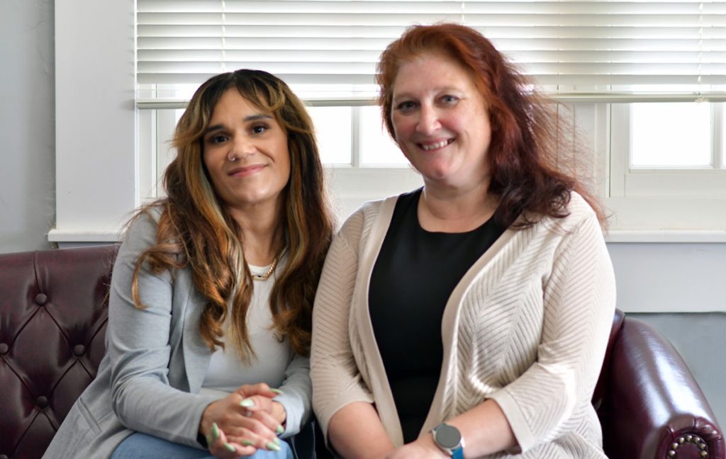Reyna and the director of the Office of Health Aging are seated on an office couch, smiling at the camera.