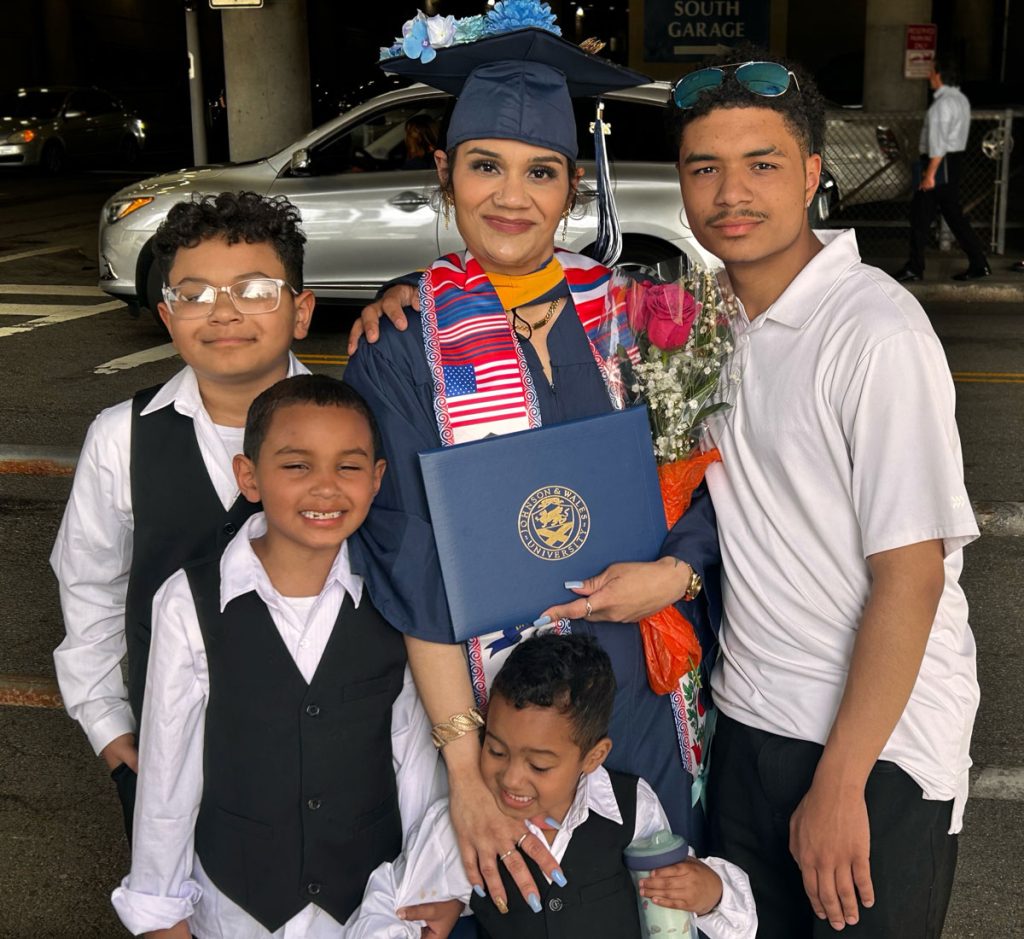 Surrounded by her four children, Reyna Salcedo proudly holds her diploma from Johnson & Wales University.