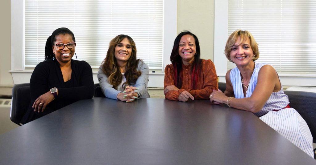 Reyna Salcedo seated at a conference table with three women who supervised her at the Office of Healthy Aging during her internship.