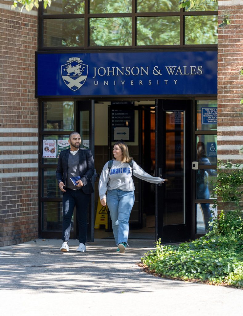 McKenzie Thibeault and a male student exit the Friedman Center building at the Johnson & Wales University Harborside Campus.