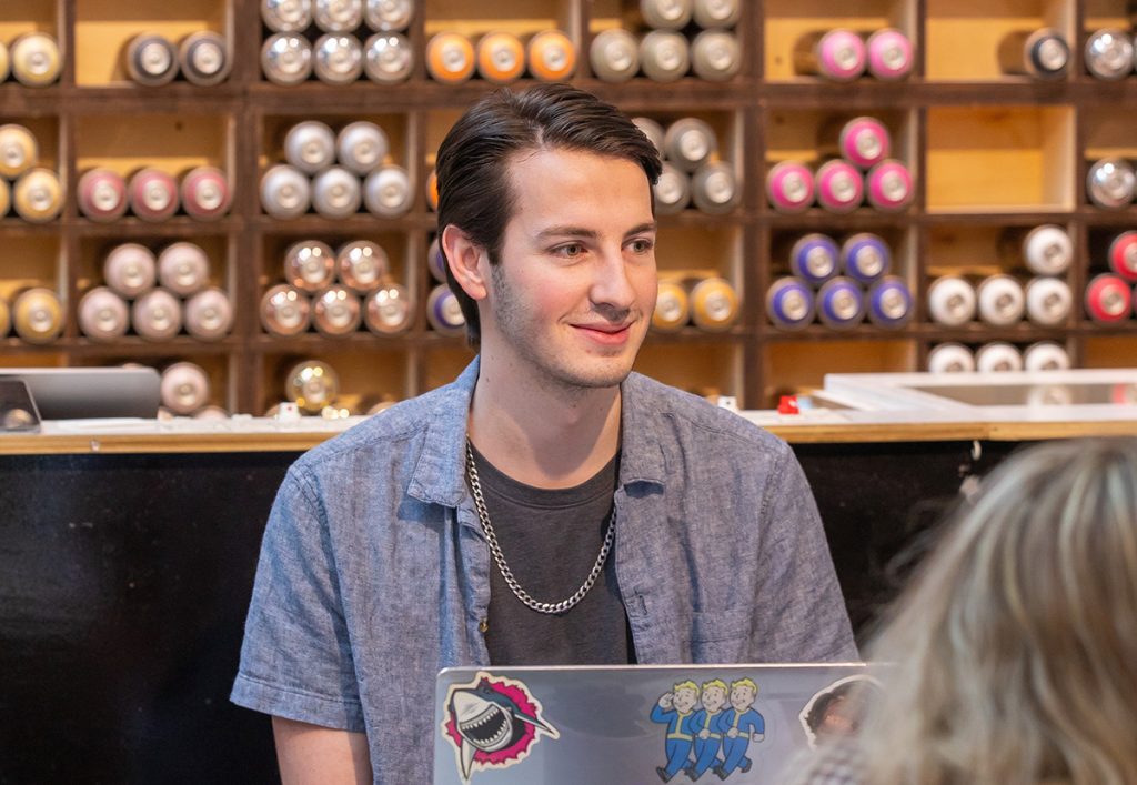 Young man with a computer in a retail space.