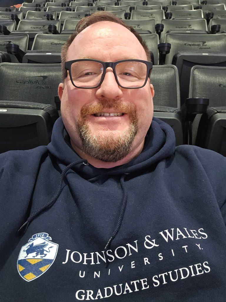 Joseph Presler wearing his Johnson & Wales University Graduate Studies sweatshirt.