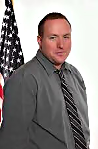 Joseph Presler pictured with an American flag at a time when he provided contract services for the Federal Government.