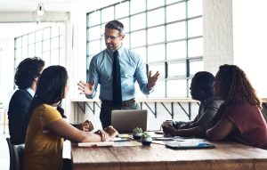 A manager leads an engaged team discussion around a conference table in a bright, modern office.