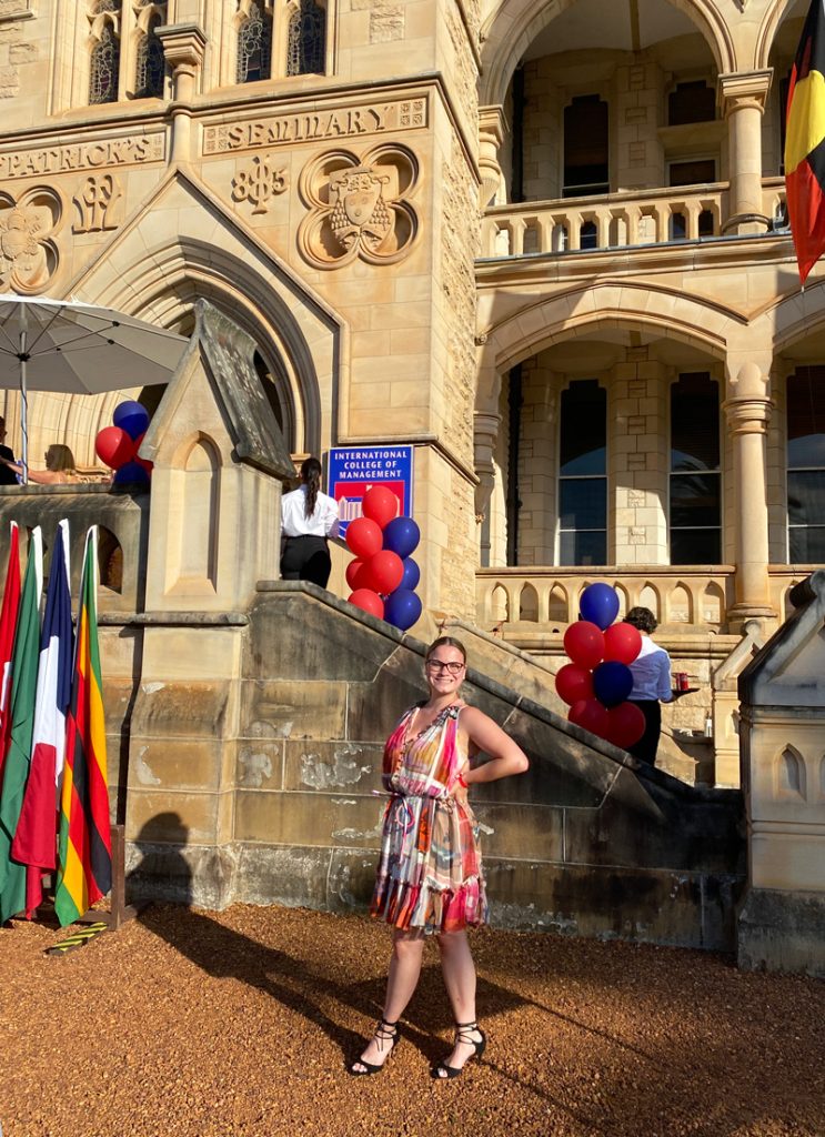 Chloe Perren in a summer dress in front of   St. Patrick's Estate at Manly in Sydney, Australia.