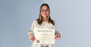 Chloe Perren holding her diploma from Johnson & Wales University.