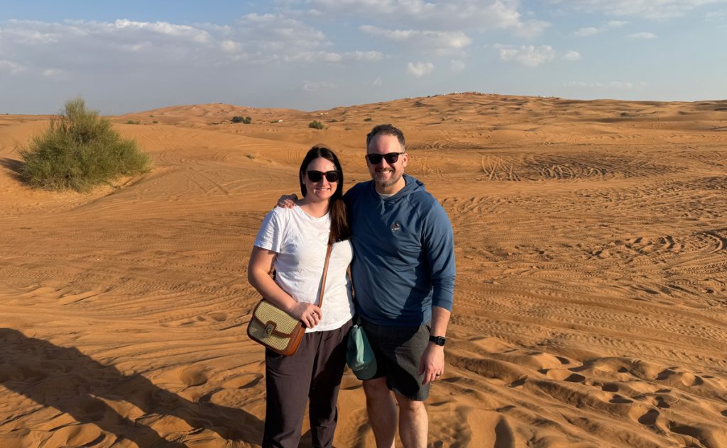 Emily Adams and Stephen Taylor standing together in the desert while touring a golf club overseas.