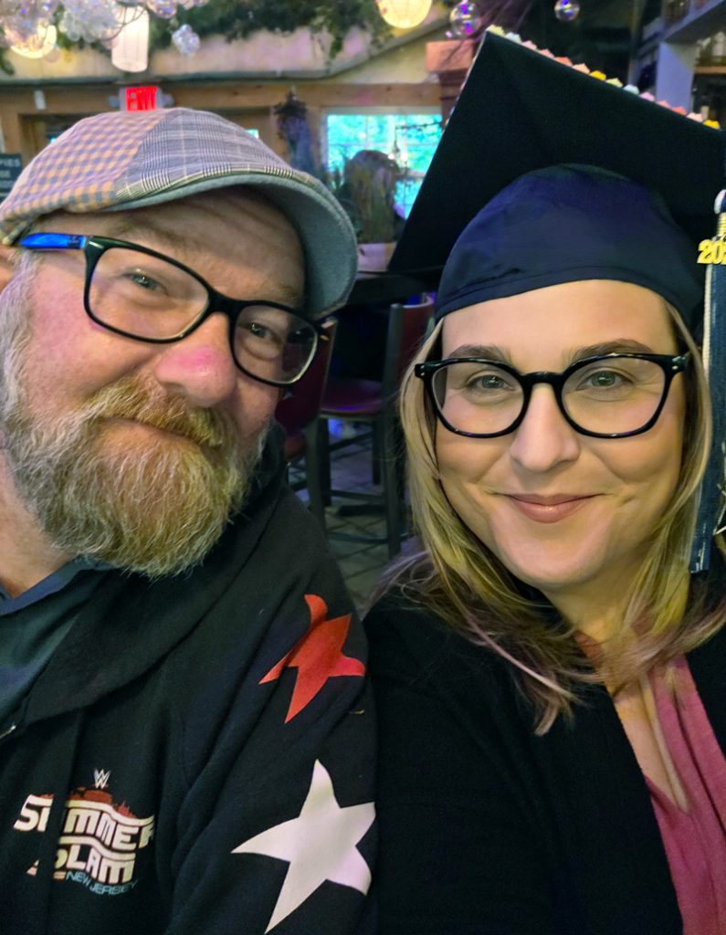 Michelle Ahearn wearing her cap and gown, in a selfie shot with husband.