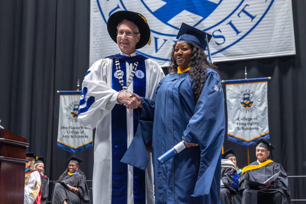 President Mathieu posing with a new female graduate onstage at the Charlotte Commencement.