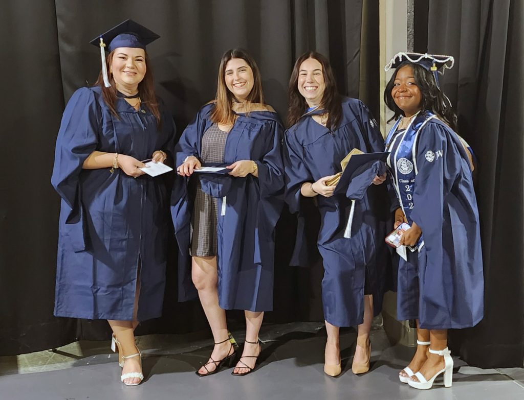 JWU Online student, McKenzie Thibeault with three other female JWU students in caps and gowns, waiting in the tunnels for the start of the commencement ceremony.