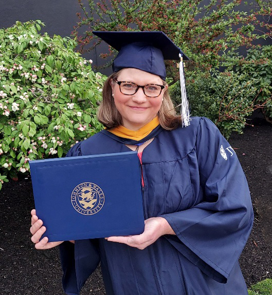 Headshot of Shannon Rhyne in cap and gown, holding her diploma.