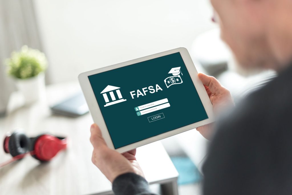 Person using a tablet to access the Free Application for Federal Student Aid (FAFSA), with the form's logo and login fields displayed on the screen.
