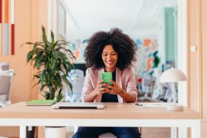 social media manager use cell phone sitting at a desk in modern office