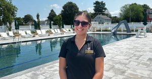 Photo of Peyton Nardella wearing sunglasses as she stands in front of the pool where she interned at the Wannamoisett Country Club.