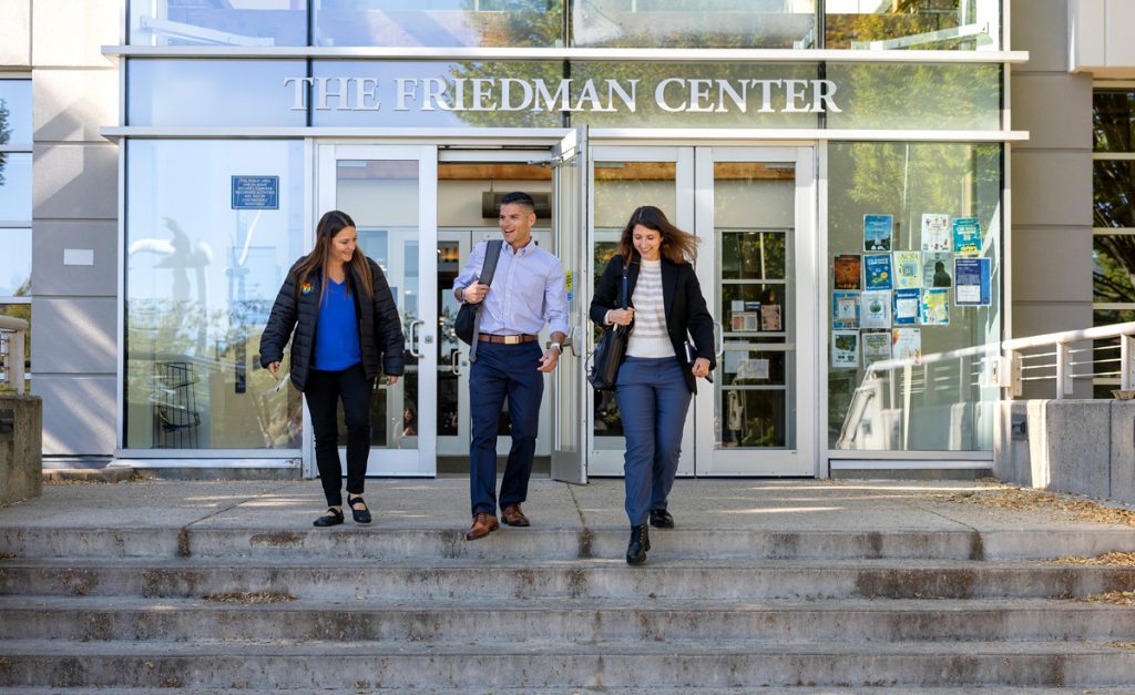 A female, a male and another female student are talking and smiling as they design the stairs of the Friedman Center on the Harborside Campus in Providence.